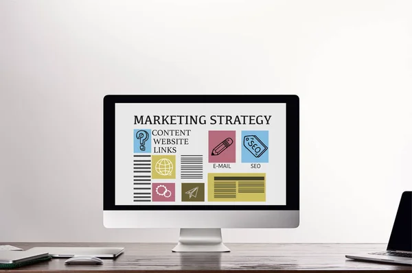 灰色の背景に職場で画面上のマーケティング戦略のイラストとアイコンを持つコンピュータ — ストック写真