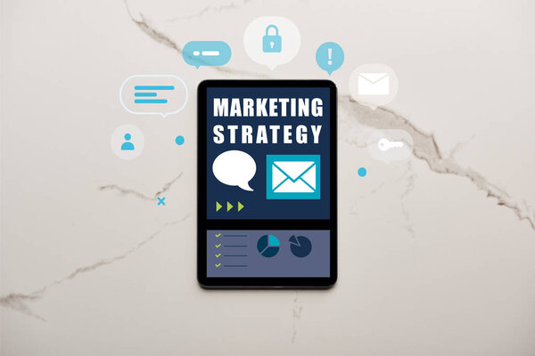 top view of digital tablet with marketing strategy illustration on white marble surface