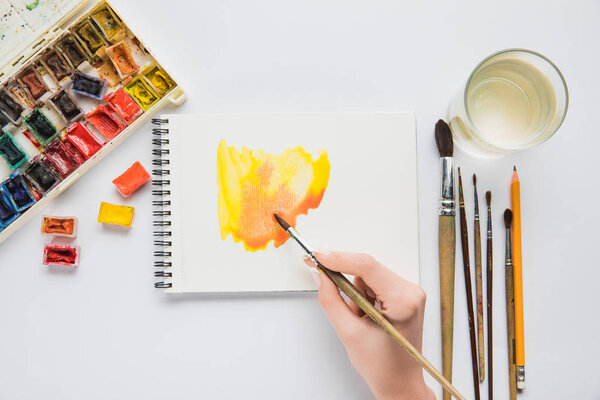 вид сверху на женский ручной рисунок в альбоме с акварельными красками и кистью
