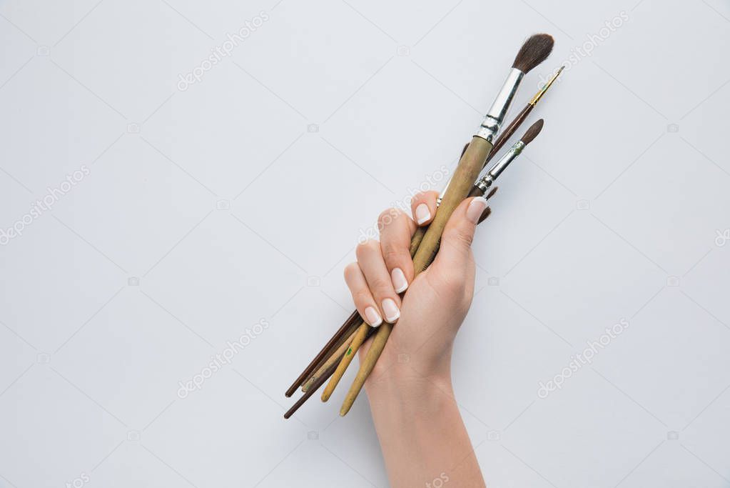 selective focus of female hand holding paint brushes on white background