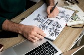 selective focus of mans hands drawing in album on wooden table next to  utensils