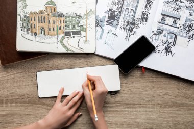 kadının el boya ve ahşap arka plan Smartphone'da Albümler kağıt üzerine çizim üstten görünüm