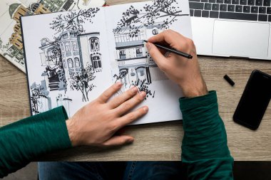 üst smartphone ve dizüstü bilgisayar yanında ahşap masa albümde çizim eller mans