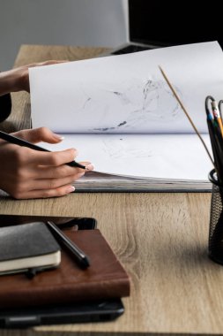 kadının el mutfak eşyaları çizim yanındaki ahşap masa üzerinde sketchbook thumbing seçici odak