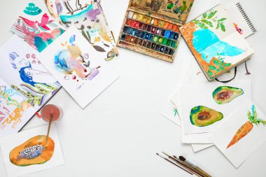 top view of colorful watercolor paintings and drawing utensils clipart