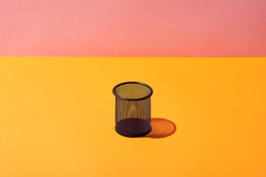 empty pencil holder on yellow surface and pink background clipart