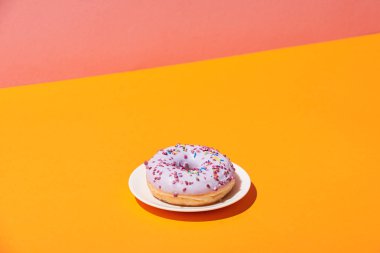 tasty donut with saucer on yellow surface and pink background clipart