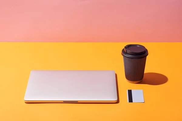 Paper Coffee Cup Laptop Credit Card Yellow Surface Pink Background — Φωτογραφία Αρχείου
