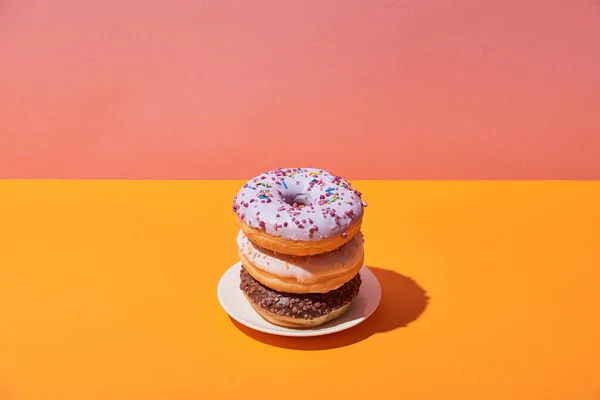 美味的甜甜圈在茶托上黄色的书桌和粉红色的背景 — 图库照片