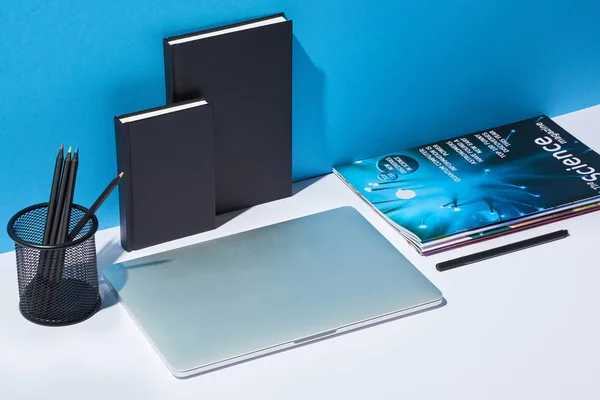 笔记本电脑 商业报纸 铅笔架和笔记本在白色的办公桌和蓝色背景 — 图库照片