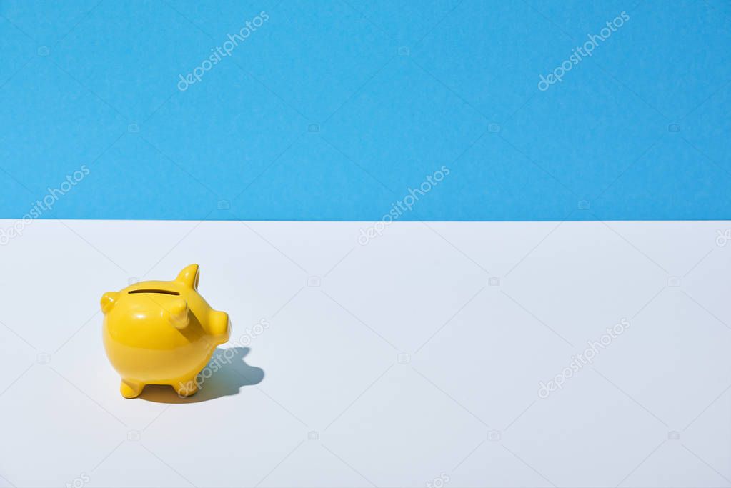 yellow piggy bank on white desk and blue background