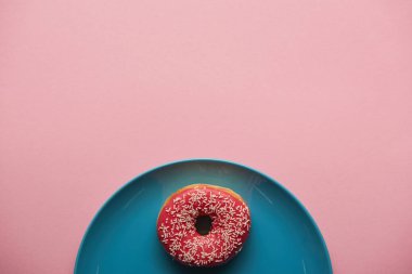 mavi plaka üzerinde pembe izole lezzetli donut üstten görünüm 