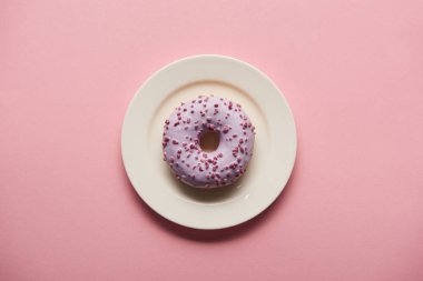 pembe bir arka plan üzerinde beyaz tabakta lezzetli donut üstten görünüm