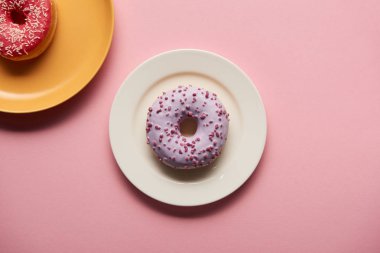 top view of tasty donuts on plates on pink background clipart