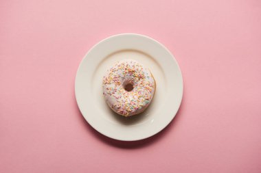 Pembe arka planda beyaz tabakta lezzetli donut manzarası 