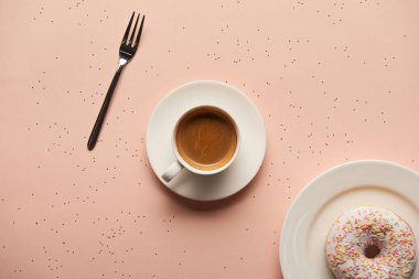 tatlı çörek yakınındaki fincan kahve ve çatal üstten görünüm pembe bir arka plan üzerinde