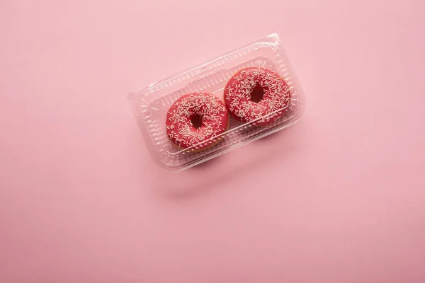 粉红色背景上的甜釉面甜甜圈的顶部视图 — 图库照片