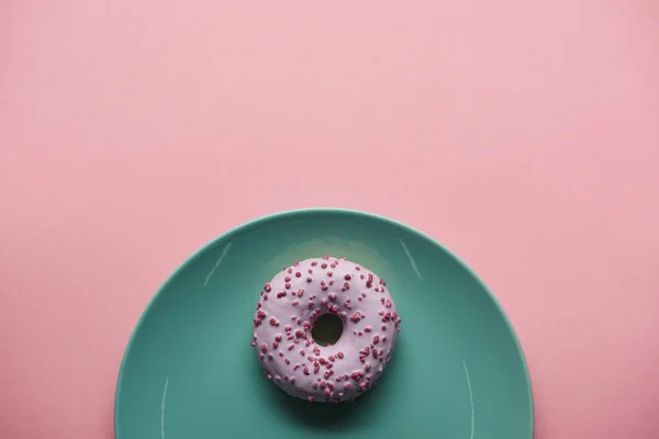在粉红色的蓝色盘子上的釉面甜甜圈的顶部视图 — 图库照片