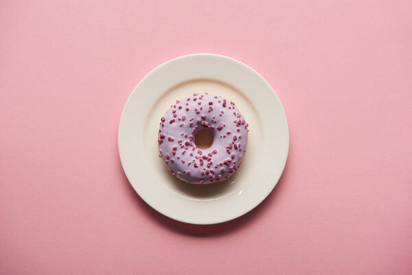 top view of tasty donut on white plate on pink background