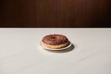 glazed chocotale doughnut with sprinkles on white table  clipart