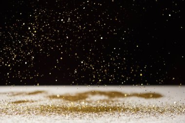 selective focus of bright sparkles falling on white table isolated on black  clipart