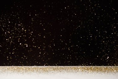 seçici odak altın sparkles beyaz masa üstünde siyah izole düşüyor 