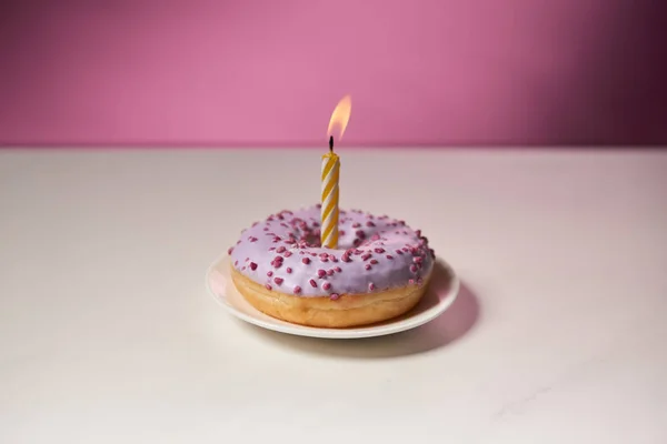 Горящая Свеча Середине Пончика Брызгами Белом Столе Розовом Фоне — стоковое фото