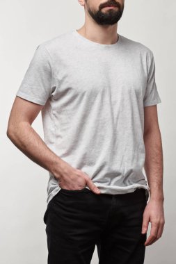 Kırpılan beyaz t-shirt gri izole kopya alanı ile cebinde elinde olan adam görünümünü
