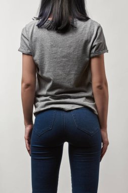 arkadan görünüşü genç kadın kot ve t-shirt üzerinde beyaz izole kopya alanı ile gri