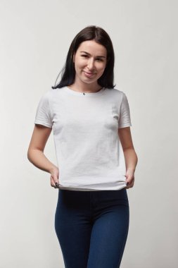 Beyaz t-shirt gri izole kamera bakarak kopya alanı ile gülümseyen genç kadında güzel