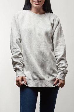 Kırpılan görünümü gri hoodie ile üzerine beyaz izole kopya alanı içinde gülümseyen genç kadın