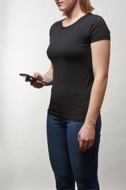 Genç kadının siyah t-shirt üzerinde beyaz izole smartphone kullanarak kopya alanı ile kısmi görünümü