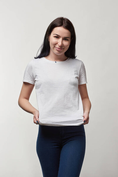 beautiful smiling young woman in white t-shirt with copy space looking at camera isolated on grey