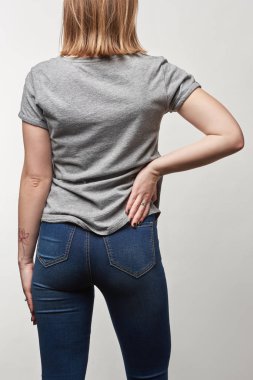 Arkadan görünüm sıradan gri t-shirt genç kadının üzerinde beyaz izole kopya alanı ile