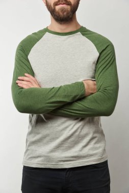 partial view of man with arms crossed in raglan sleeve baseball shirt with copy space isolated on grey clipart