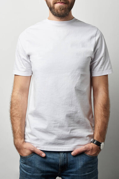 cropped view of man with hands in pockets in white t-shirt with copy space isolated on grey