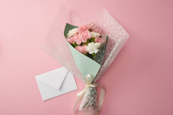 top view of beautiful tender flower bouquet and white envelope isolated on pink 