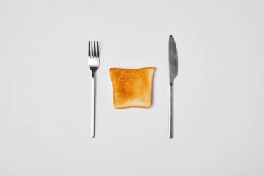 top view of grilled crispy toast with fork and knive on grey background clipart