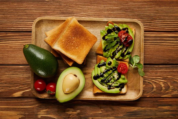 ahşap arka plan üzerinde avokado ile tost, cherry domates, üstten görünüm