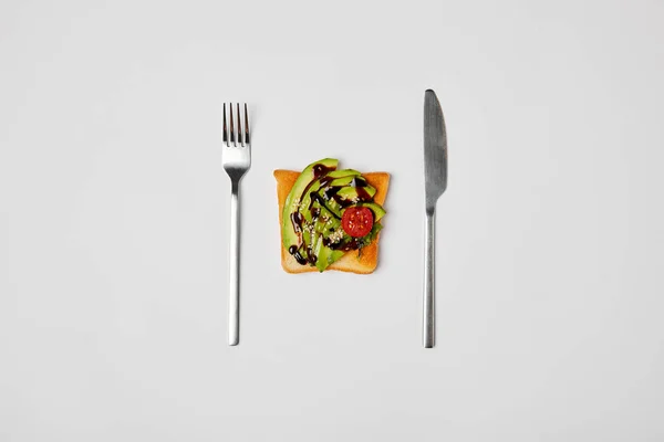 アボカド チェリー トマト フォーク ナイフ グレーの分離とトーストの平面図 — ストック写真
