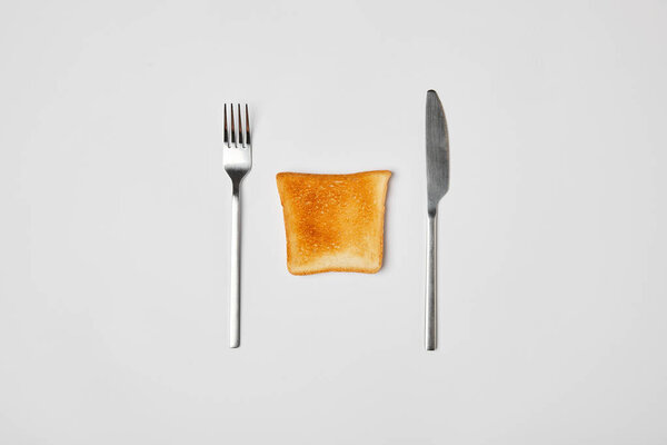 top view of grilled crispy toast with fork and knive on grey background