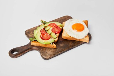 Ahşap kesme tahtası tost ve gri arka plan üzerine çırpılmış yumurta ile seçici odak