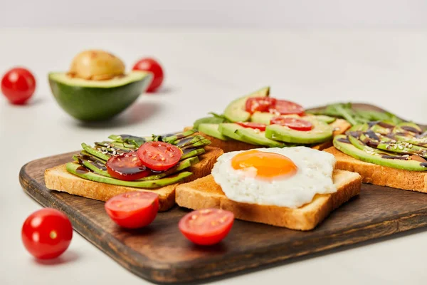 Selektiver Fokus Des Holzschneidebretts Mit Toasts Rührei Kirschtomaten Und Avocado — Stockfoto