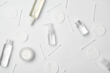 Top view of different cosmetic bottles, cotton sticks and cosmetic pads on white background clipart