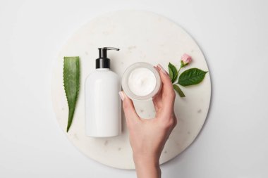 kısmi görünümünü el kremi konteyner kozmetik dağıtıcılar, aloe vera yaprağı ve gül çiçek ile yakınındaki beyaz yüzeyi 