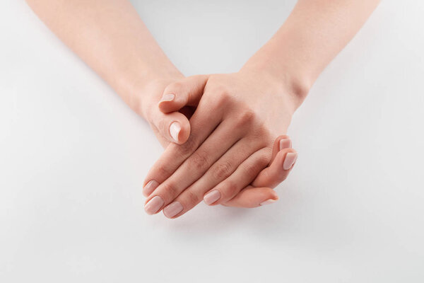 Partial view of female clanched hands on white background 