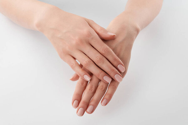 Partial view of female well-cared clanched hands on white background 