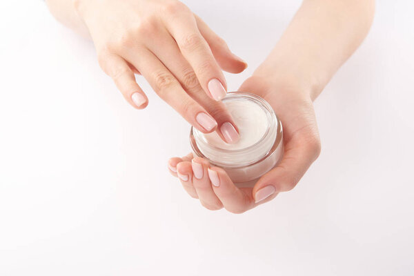 Partial view of woman applying hand cream on white background