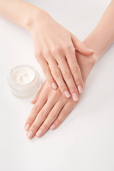 Partial view of woman applying cosmetic cream on white background