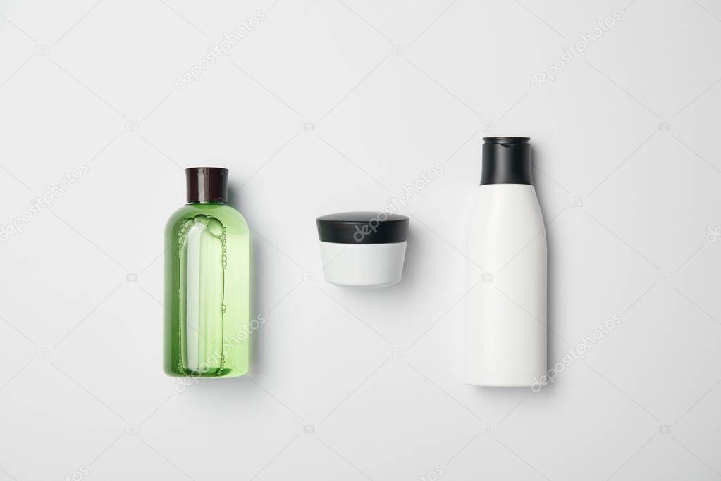 Top view of different cosmetic bottles on white background